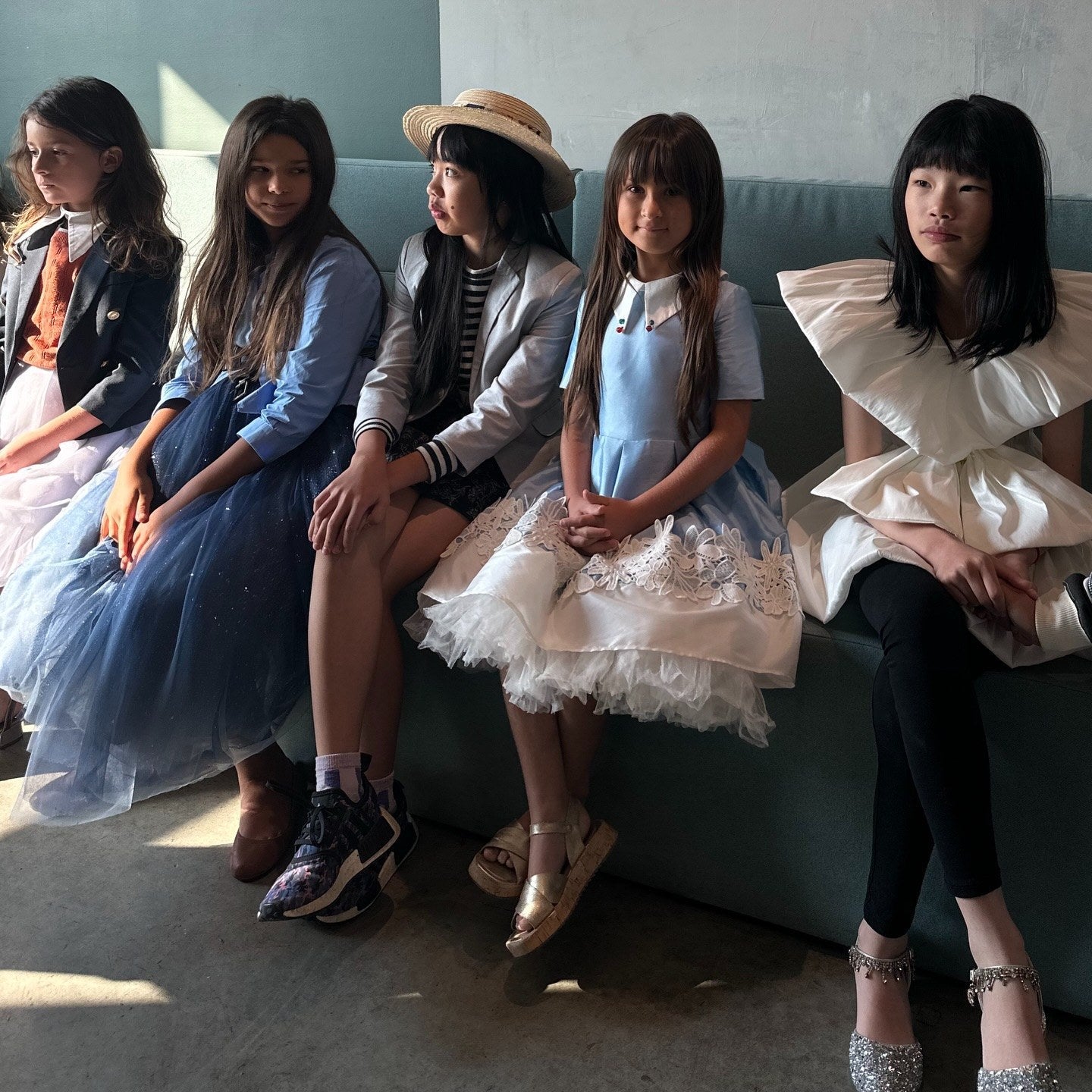 Backstage at Vancouver Kids Fashion Week 2026: five girls in blazers, big collars, tulle and a sculptural white bow dress